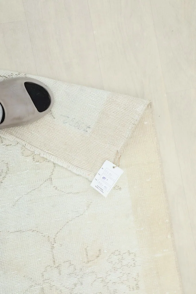 Close-up of the rug's corner with a shoe for scale, showing the professionally cleaned label.