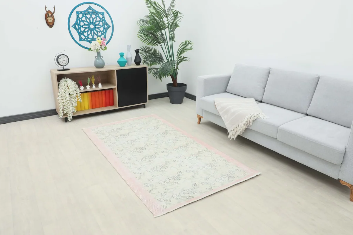 Ivory and rose floral rug placed in a modern living room setting with a light gray sofa.