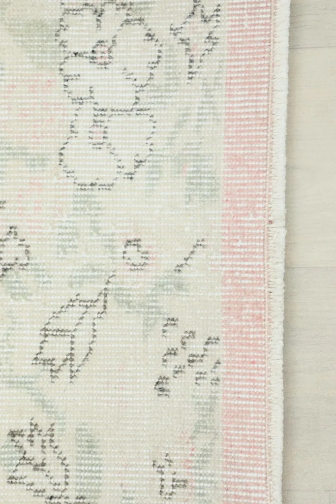 Close-up of the rose border and the transition to the ivory field, showing the rug's edge.