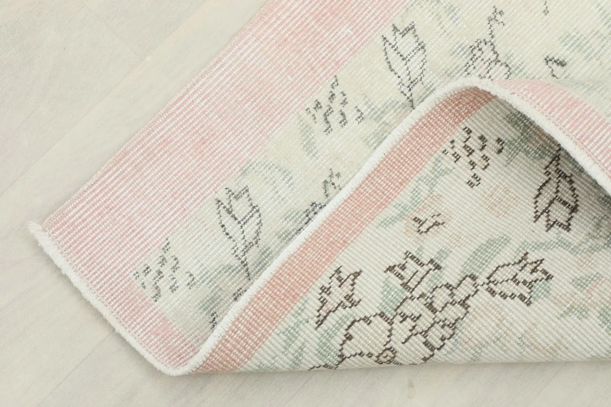 Corner of the rug folded back, displaying the cotton foundation and the reverse side.