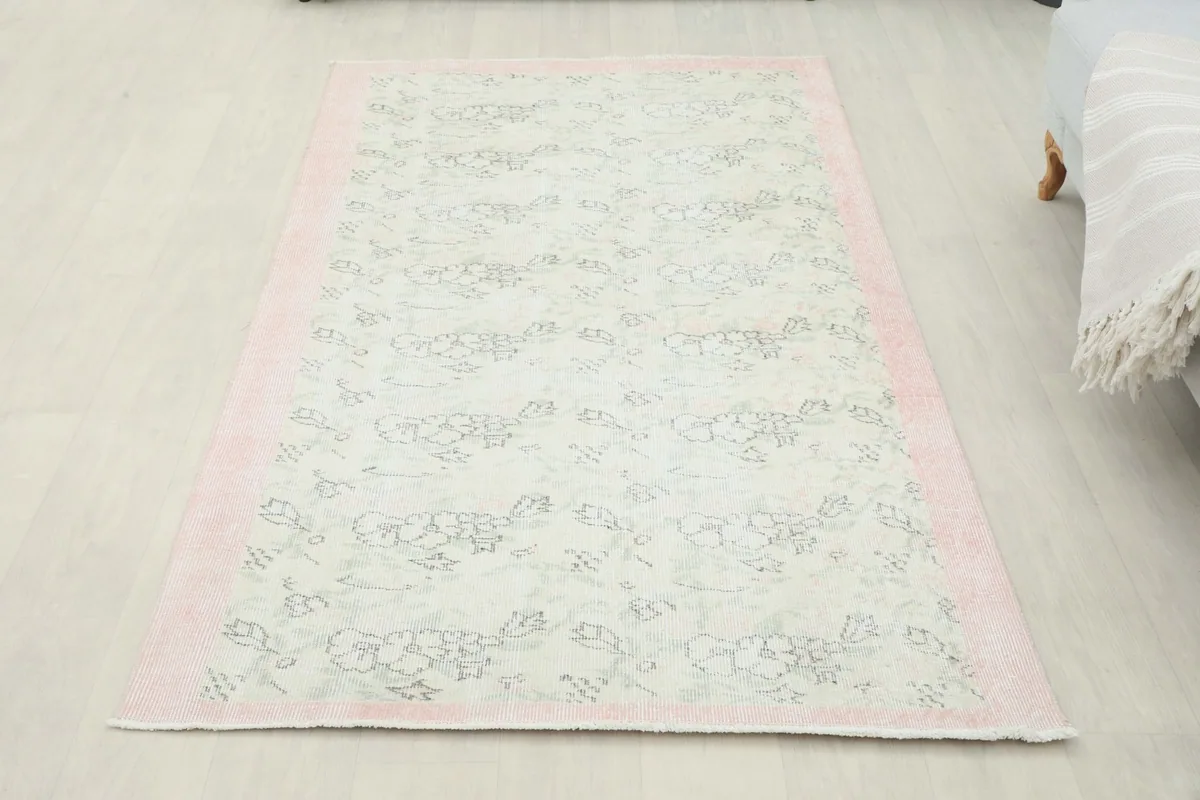 Full overhead view of the ivory and rose vintage rug on a light-colored floor, showing its entire design.