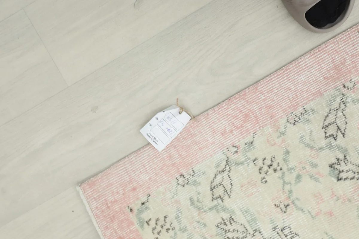 Overhead view of a corner of the rug with a product tag, showing the intricate details.