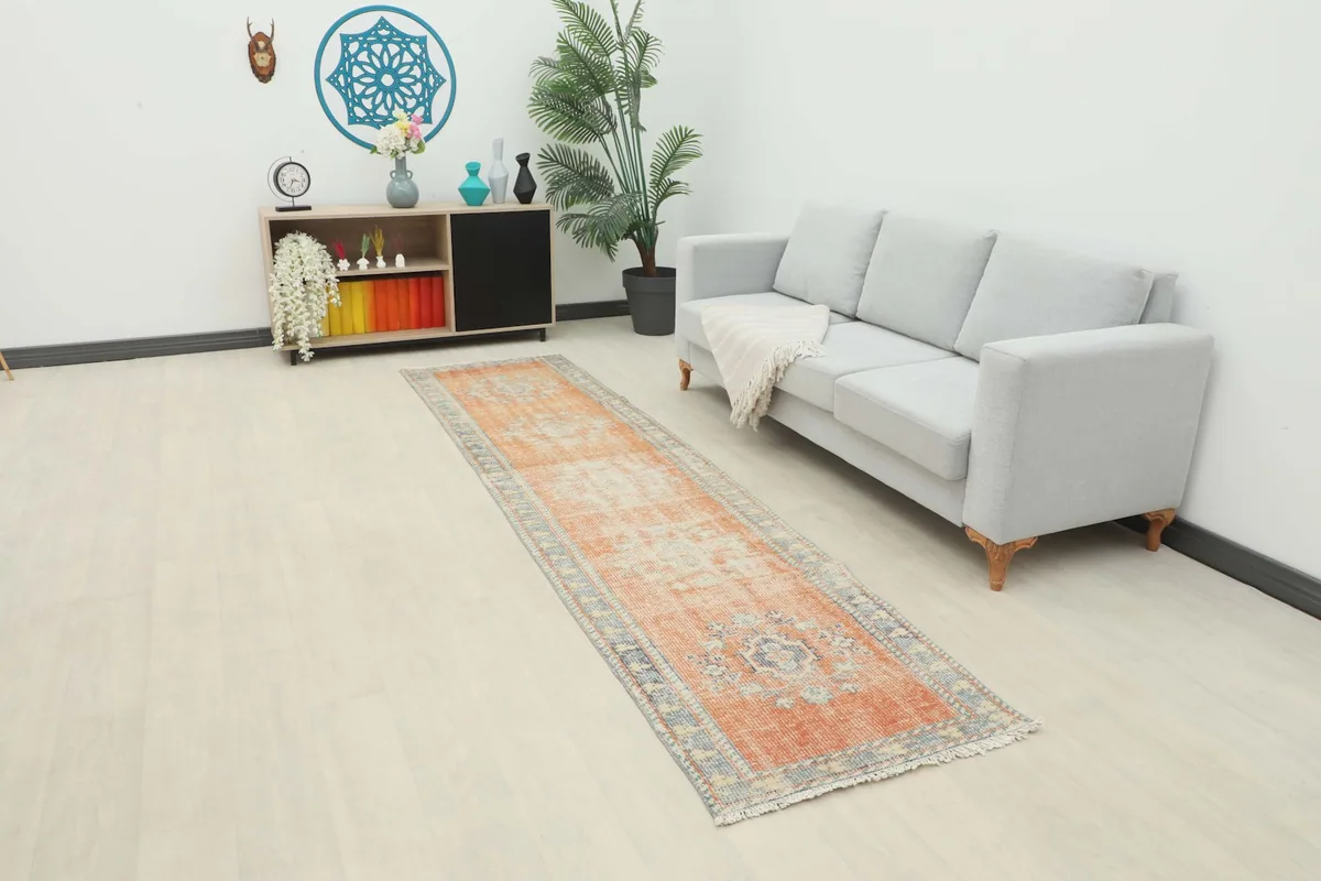 Long view of the rust geometric runner rug placed in a modern living room setting with a light gray sofa.