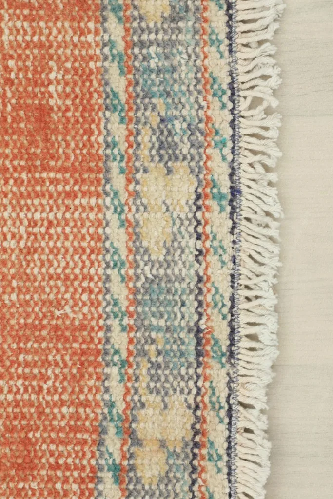 Close-up of the rug's edge, revealing the short, natural fringes and the woven border details.