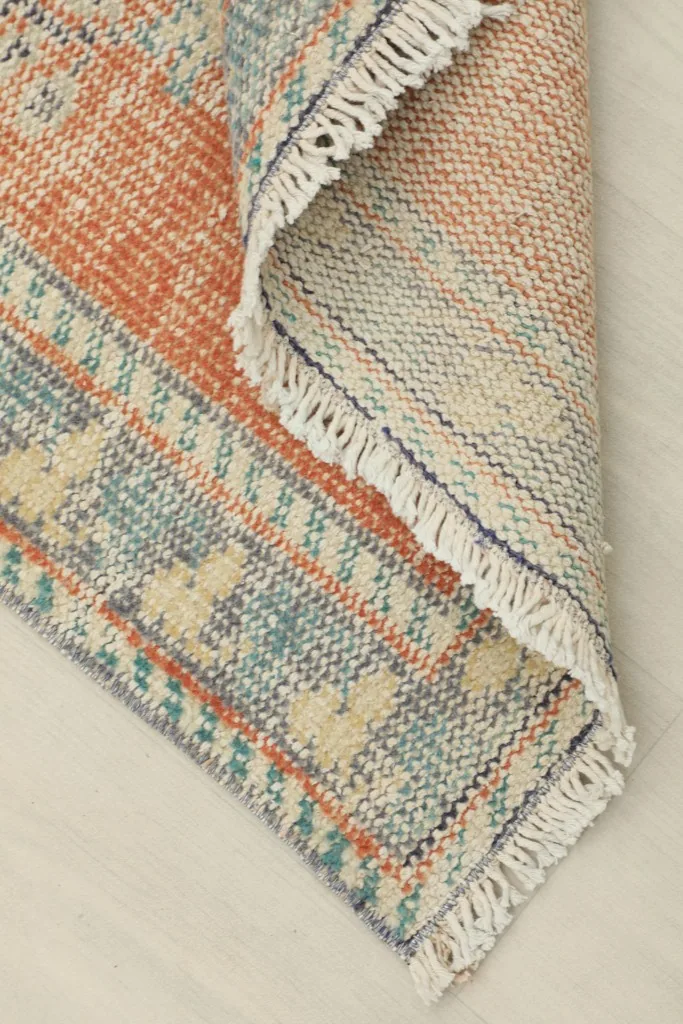 View of the rug folded to show the back of the hand-knotted wool pile on a cotton foundation.