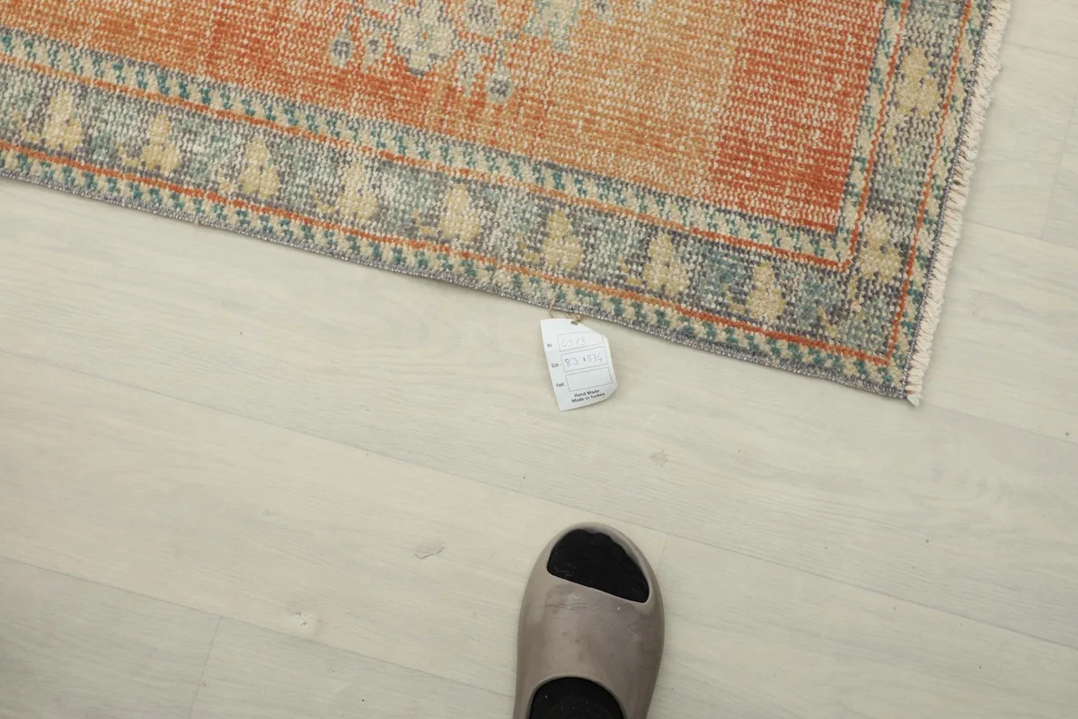 Overhead view showing the rug's scale next to a foot, emphasizing its length and narrow profile.