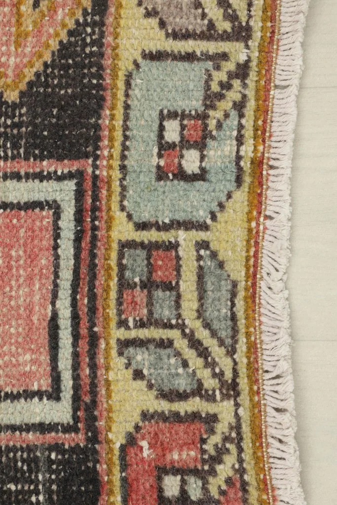 Detail of the rug's outer border design and the short, hand-knotted fringe