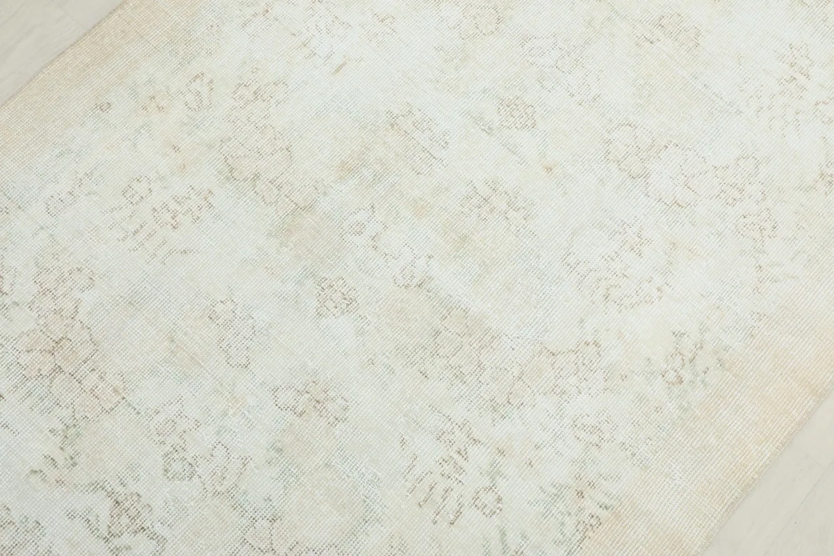 Detailed view of the rug's center, revealing the subtle beige and tan hues within the faded patterns