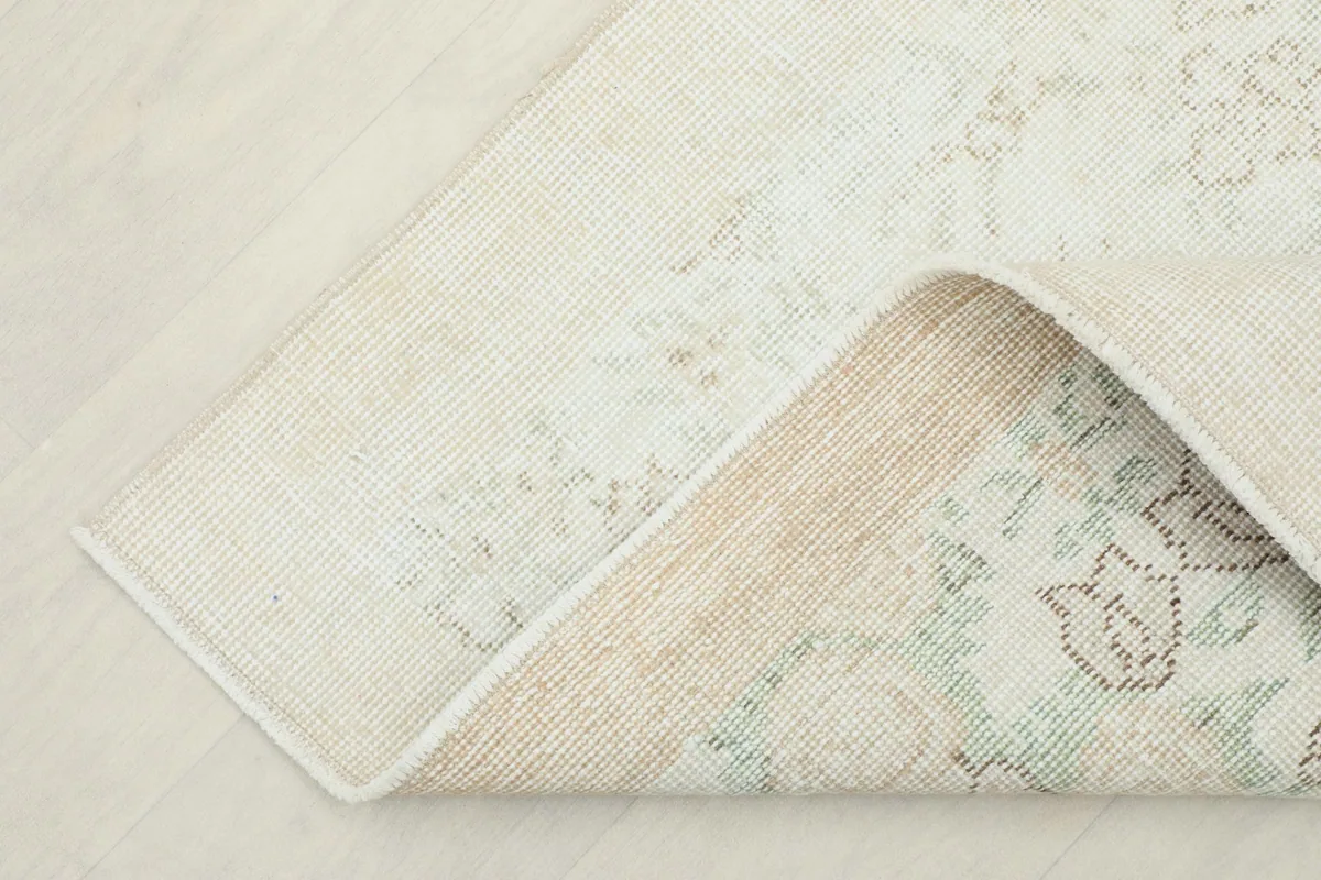 Corner of the rug folded back, revealing the cotton foundation and the reverse side of the knots