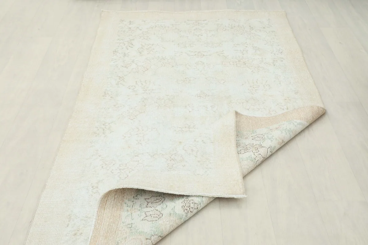 Rug partially folded, displaying the wool pile on the front and the sturdy cotton foundation underneath