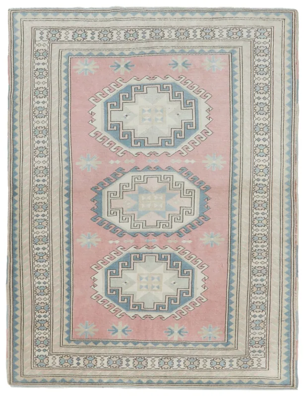 Full top view of the vintage pink Anatolian rug with blue and ivory geometric medallions on a white background