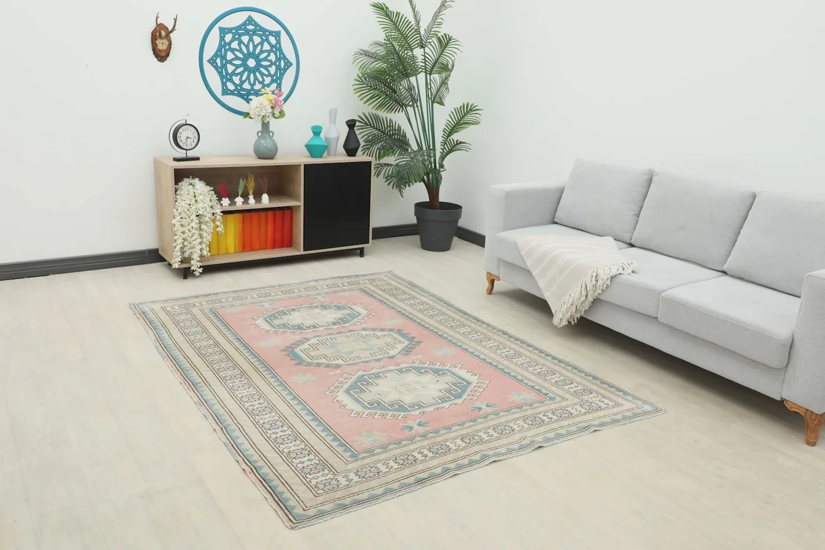 Vintage pink Anatolian rug in a room setting with a light gray sofa and wooden console