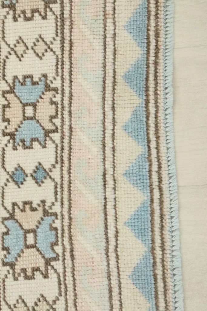 Close-up of the rug's outer border design, showing the geometric motifs and fringe