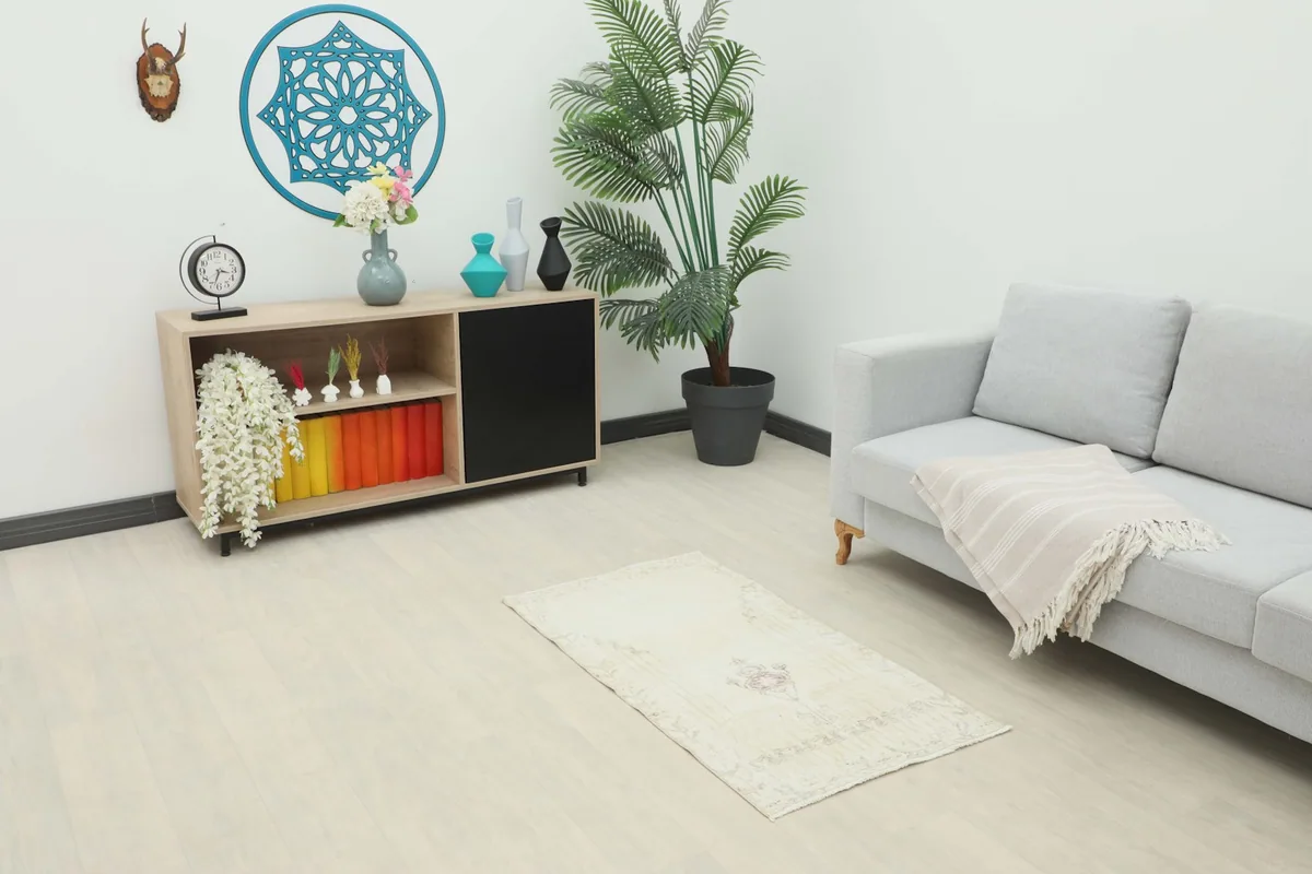 Vintage ivory and rose rug placed in a living room setting next to a sofa and cabinet