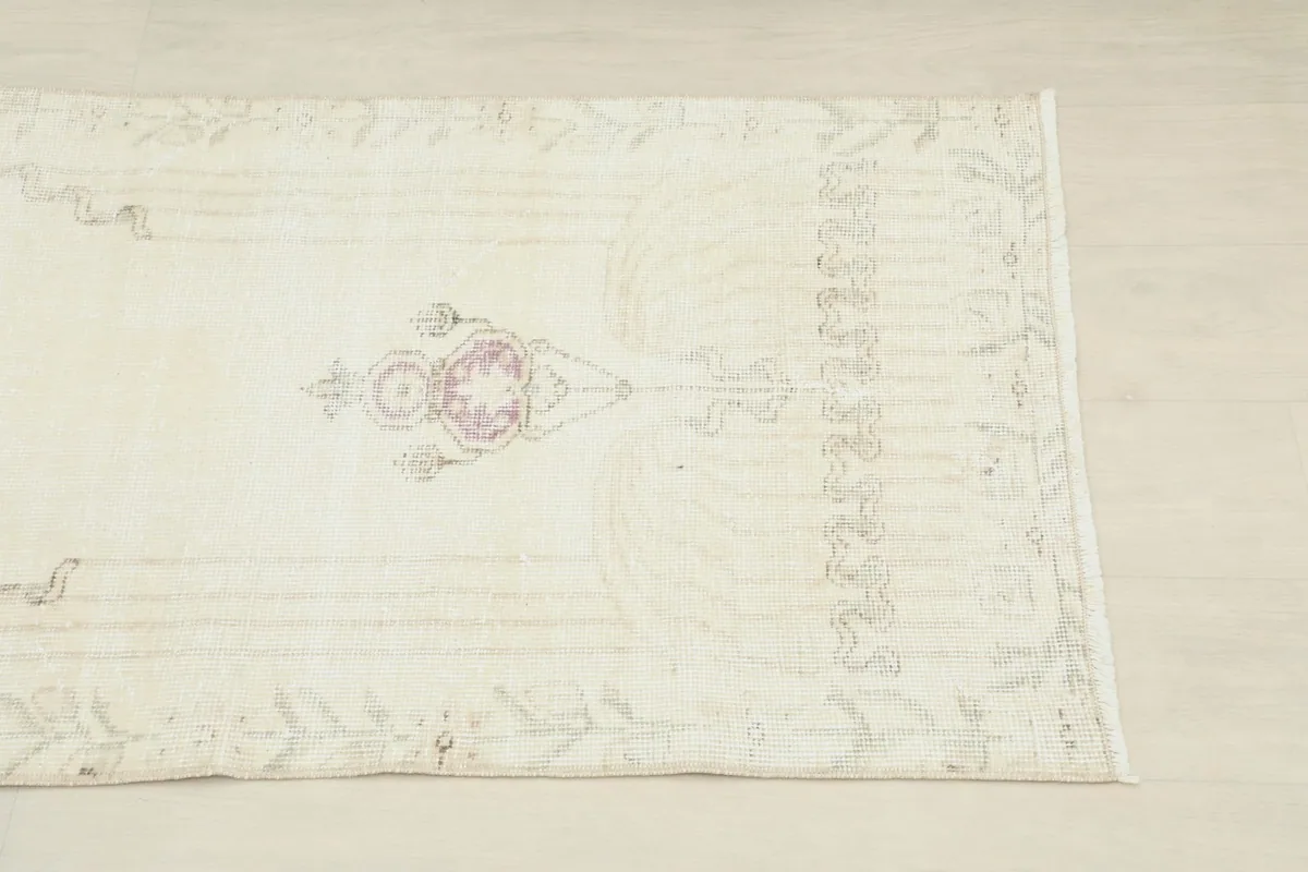 Close-up of the rug's side, revealing subtle gray border patterns and faded rose tones