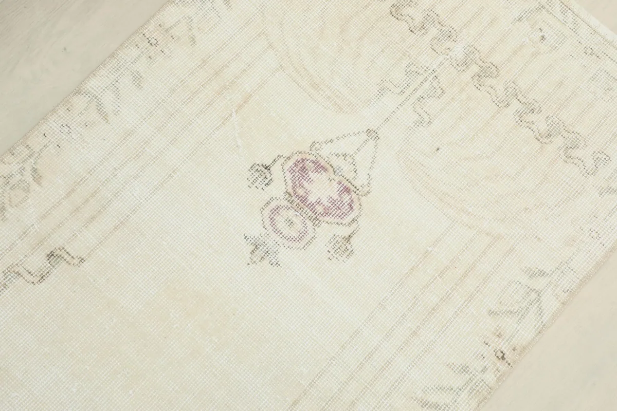 Overhead view of the central rose and gray geometric motif on the ivory field