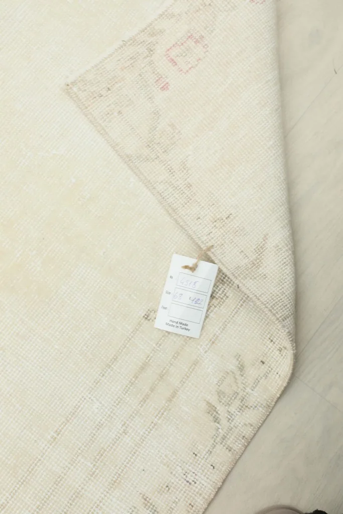Corner of the rug with a product tag, displaying information about the vintage piece