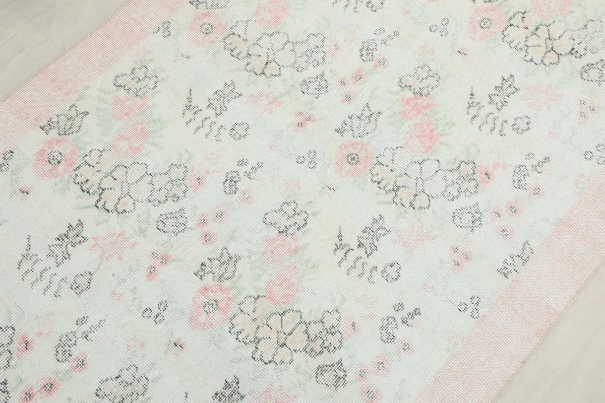 Detailed overhead shot of the rug's floral pattern, showing the ivory field and rose accents