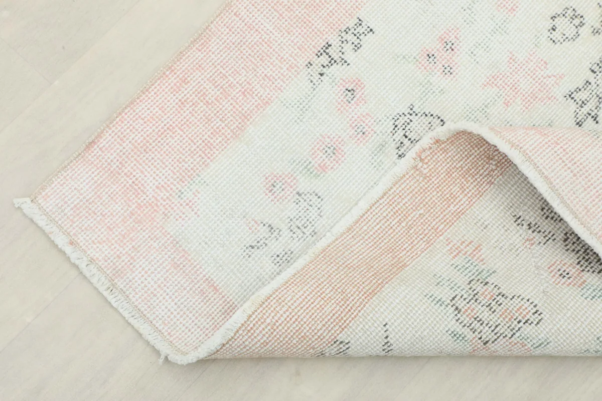 Underside view of the rug, folded to show the cotton foundation and the reverse of the hand-knotting