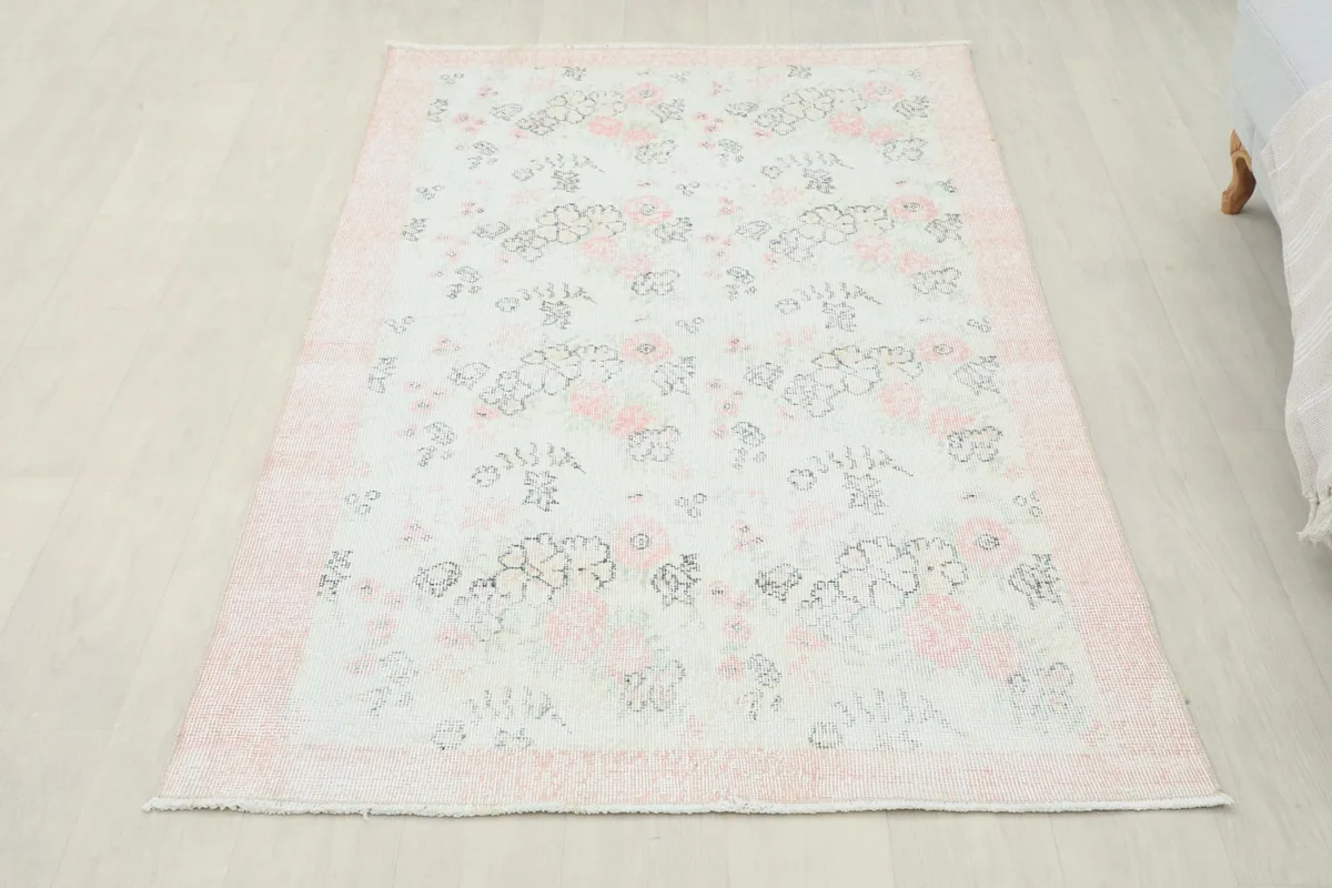 Full overhead view of the rose and ivory floral rug on a light wooden floor, showcasing its entire design
