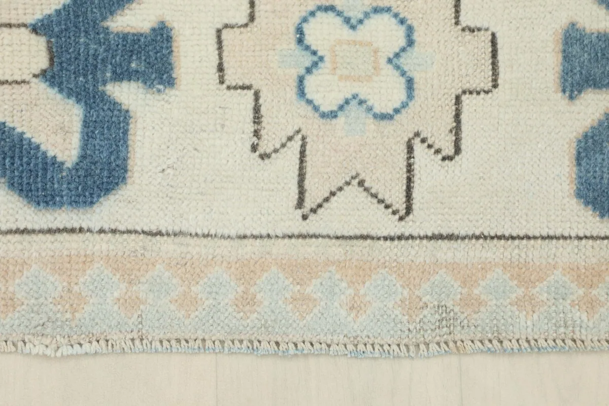 Close-up of the rug's edge, showing the intricate tan and blue patterns of the outer border