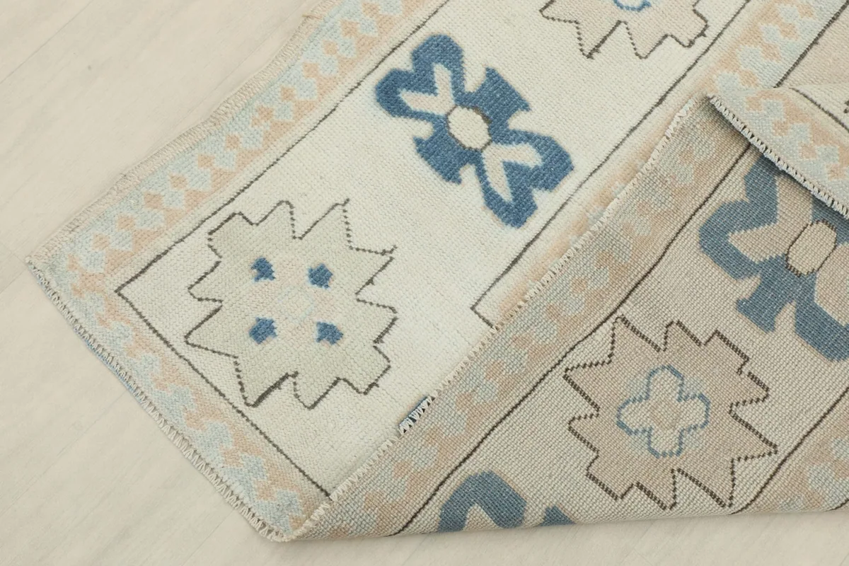 Corner of the rug folded back, revealing the hand-knotted construction and cotton foundation