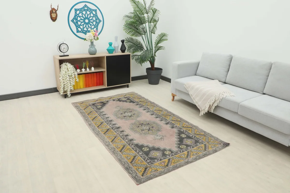 Vintage rose and gold geometric rug in a living room setting with a sofa and side table