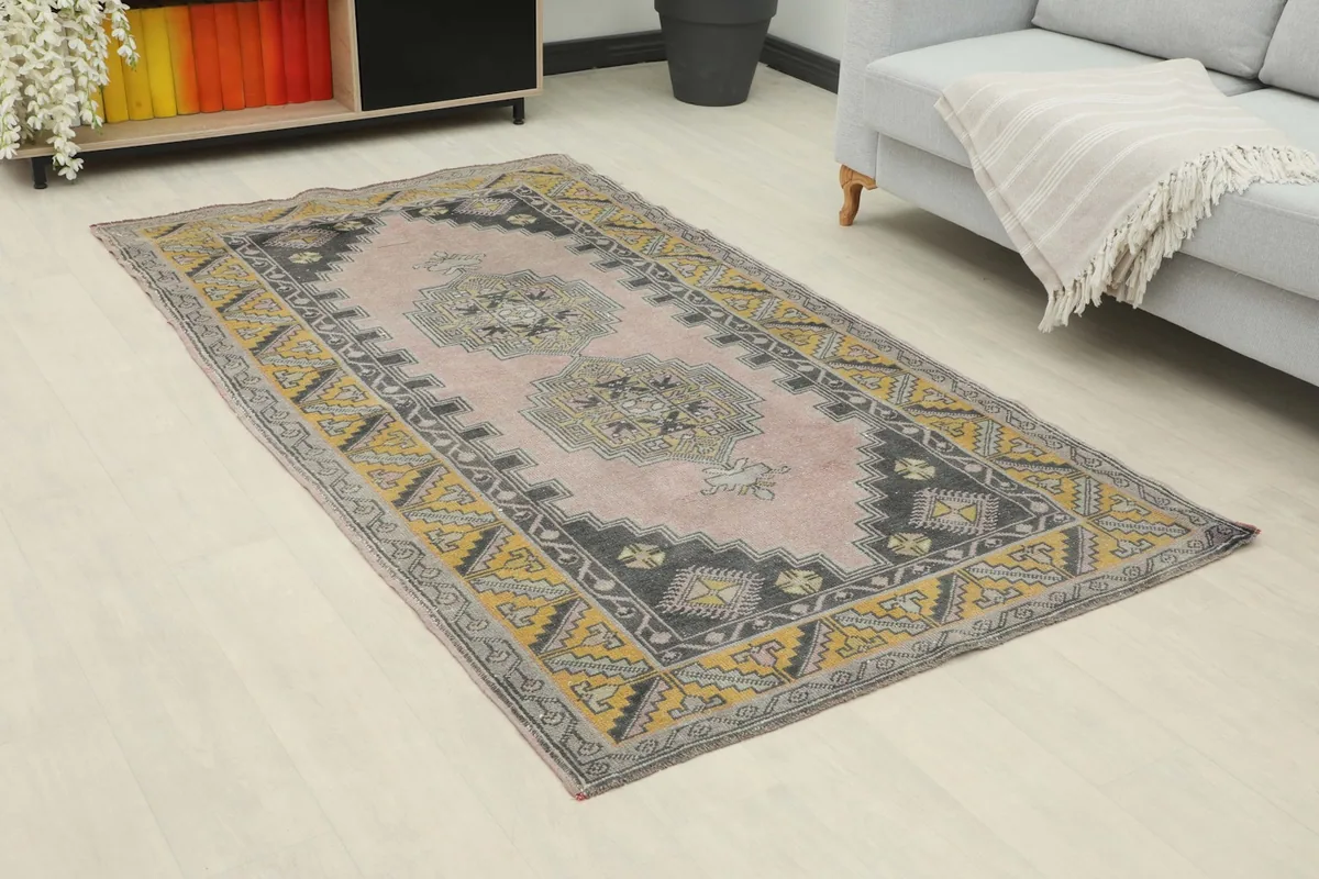 Angle view of the rose and gold geometric rug placed on a light floor in a room