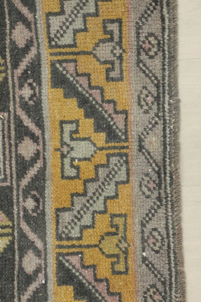 Detailed view of the gray and gold stepped geometric patterns in the rug's border