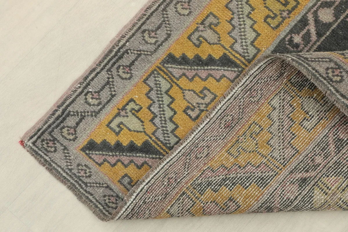 Corner of the rug folded back, showing the back of the hand-knotted wool on cotton foundation