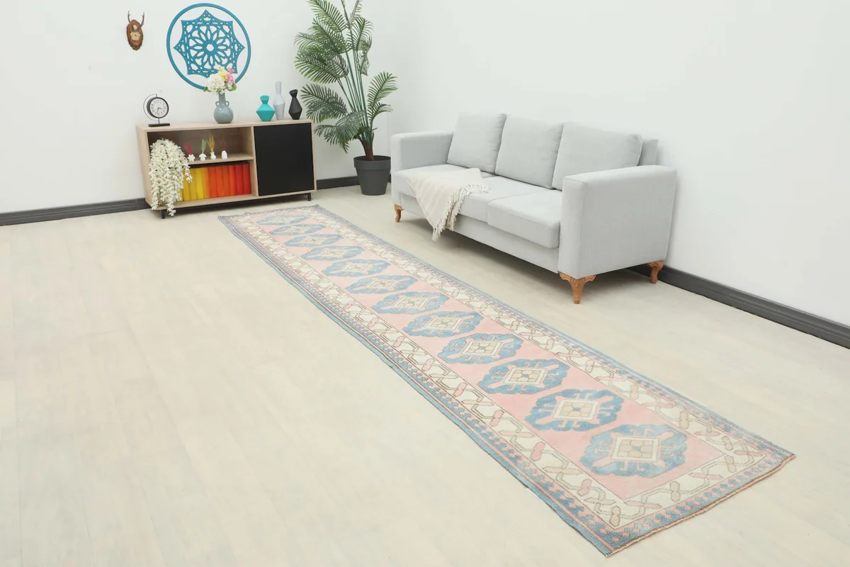 Long view of the rose and blue runner rug laid out in a modern living space with a light gray sofa and wood flooring.
