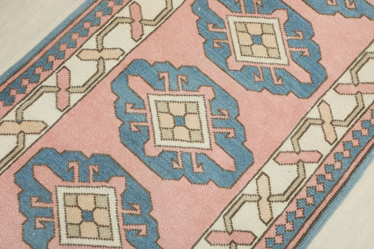 Detailed view of the repeating blue geometric medallion motifs against the rose background, with subtle variations.