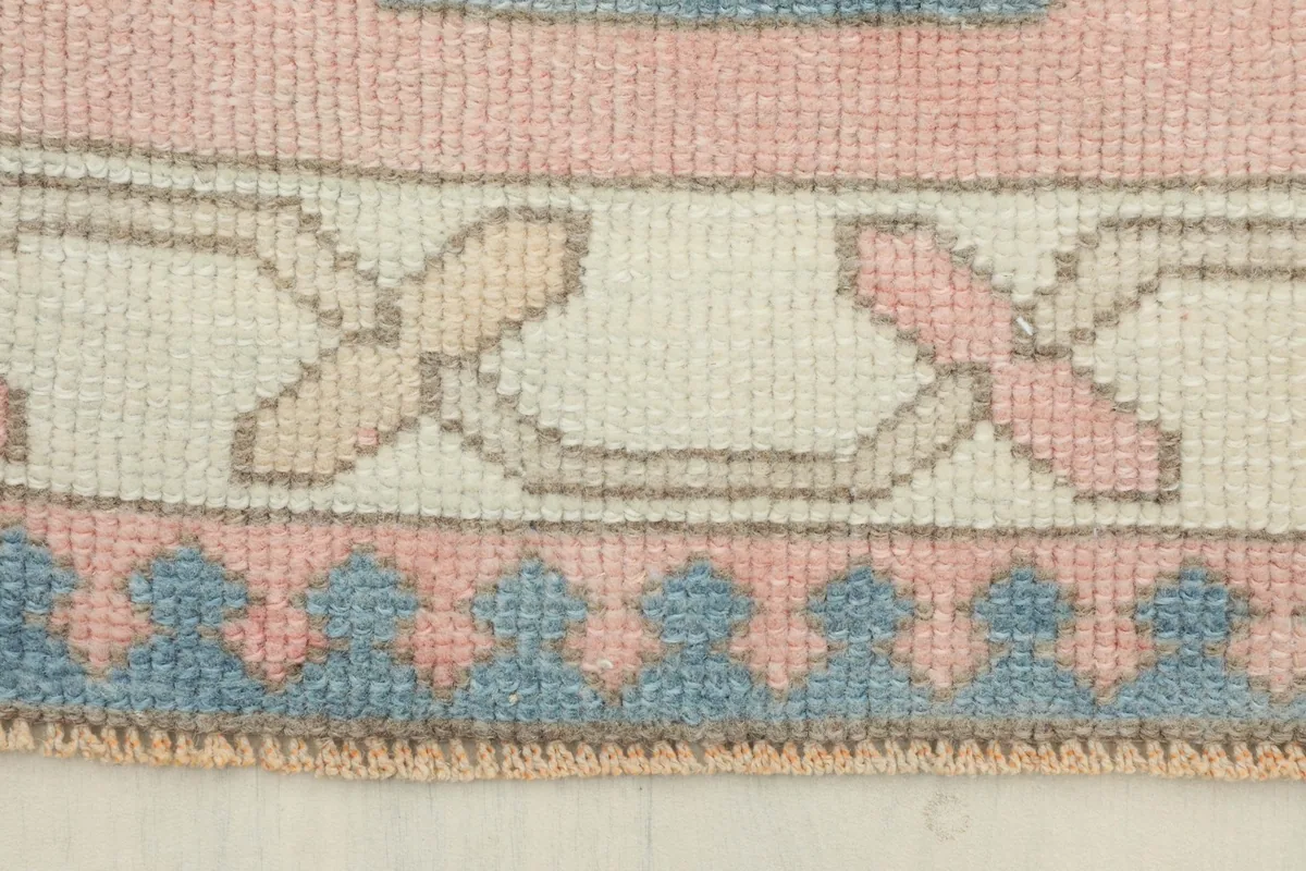 Close-up of the rug's border, showcasing the ivory and tan tribal patterns and the blue outer edge.