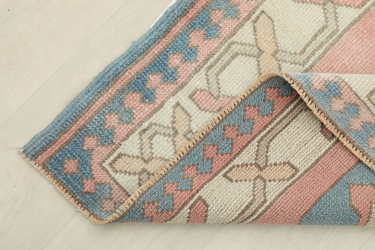 View of the rug folded back to show the cotton foundation and the reverse side of the hand-knotted wool pile.