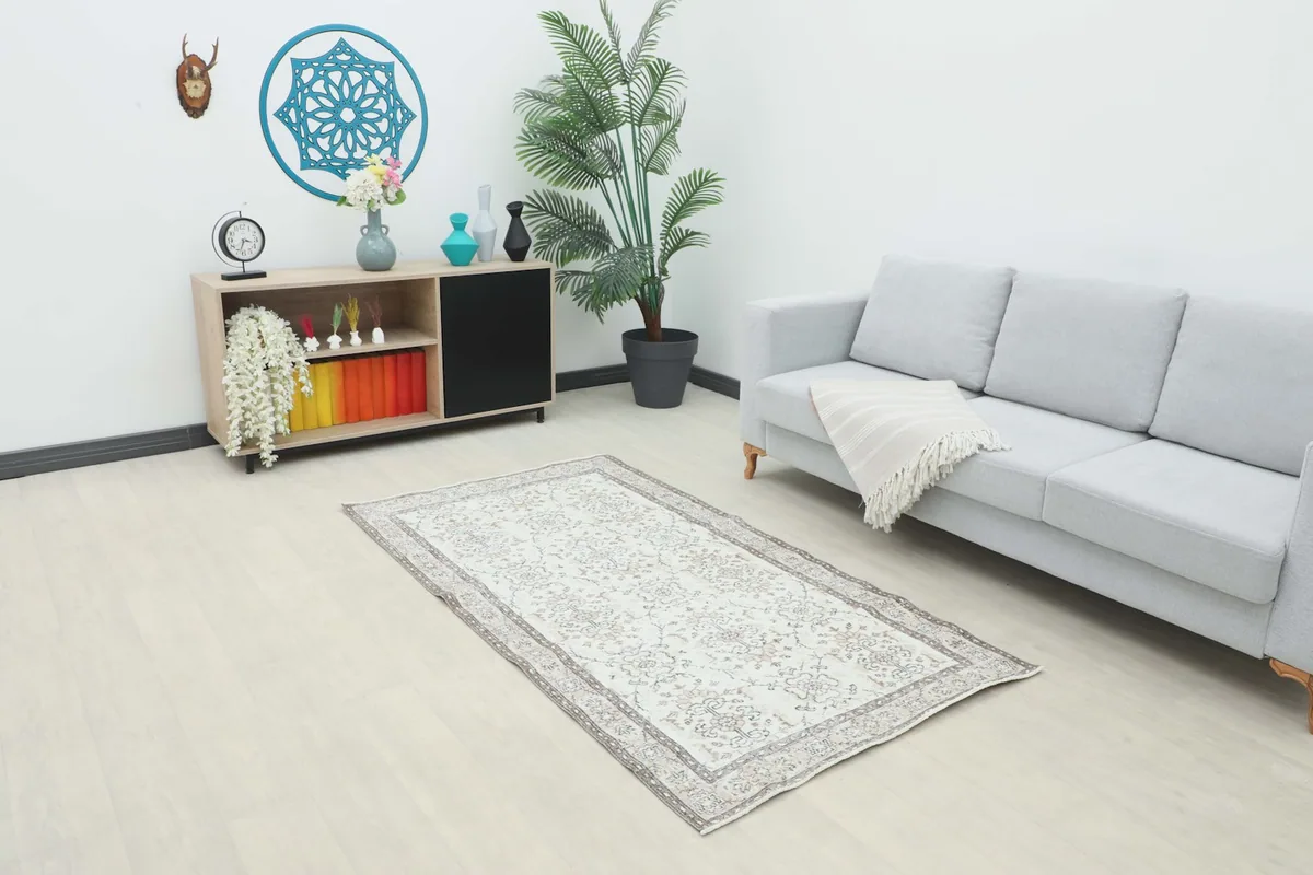 Vintage cream and gray rug displayed in a modern living room setting with a sofa and cabinet