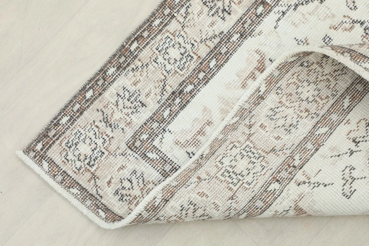 Corner of the rug folded back, revealing the backside and texture of the hand-knotted wool