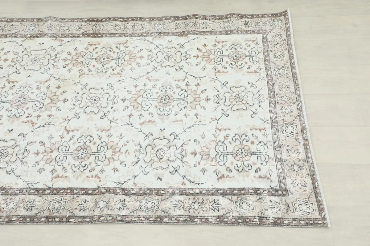 Overhead view showing the cream field, gray and tan floral motifs, and border design