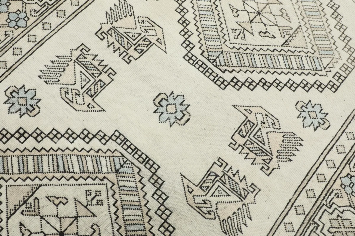 Close-up of the rug's surface, revealing the hand-knotted texture and stylized bird patterns.