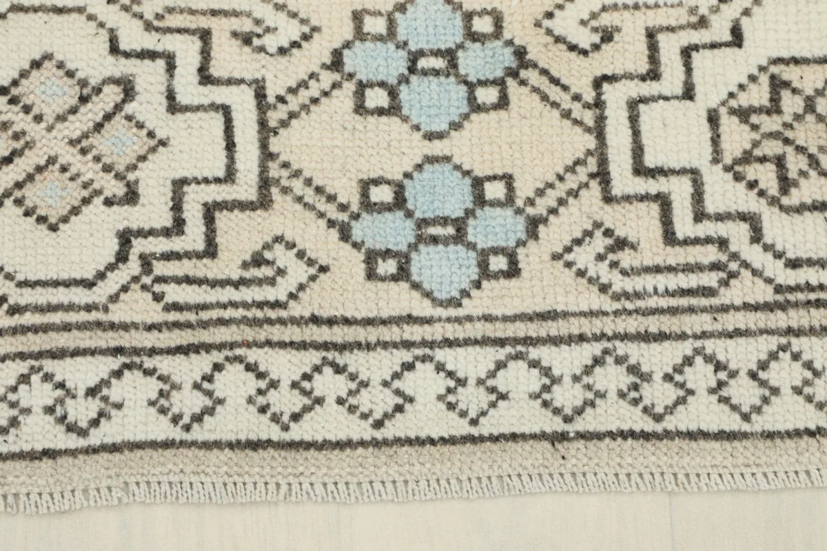 Detail of the rug's outer border, showing repeating geometric shapes and light blue patterns.