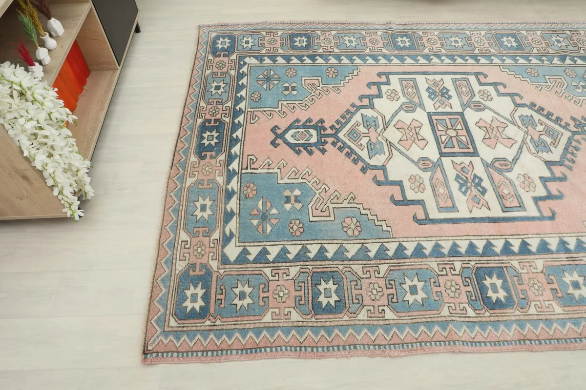 Overhead angled shot of the rose and blue vintage rug, showing its placement in a room