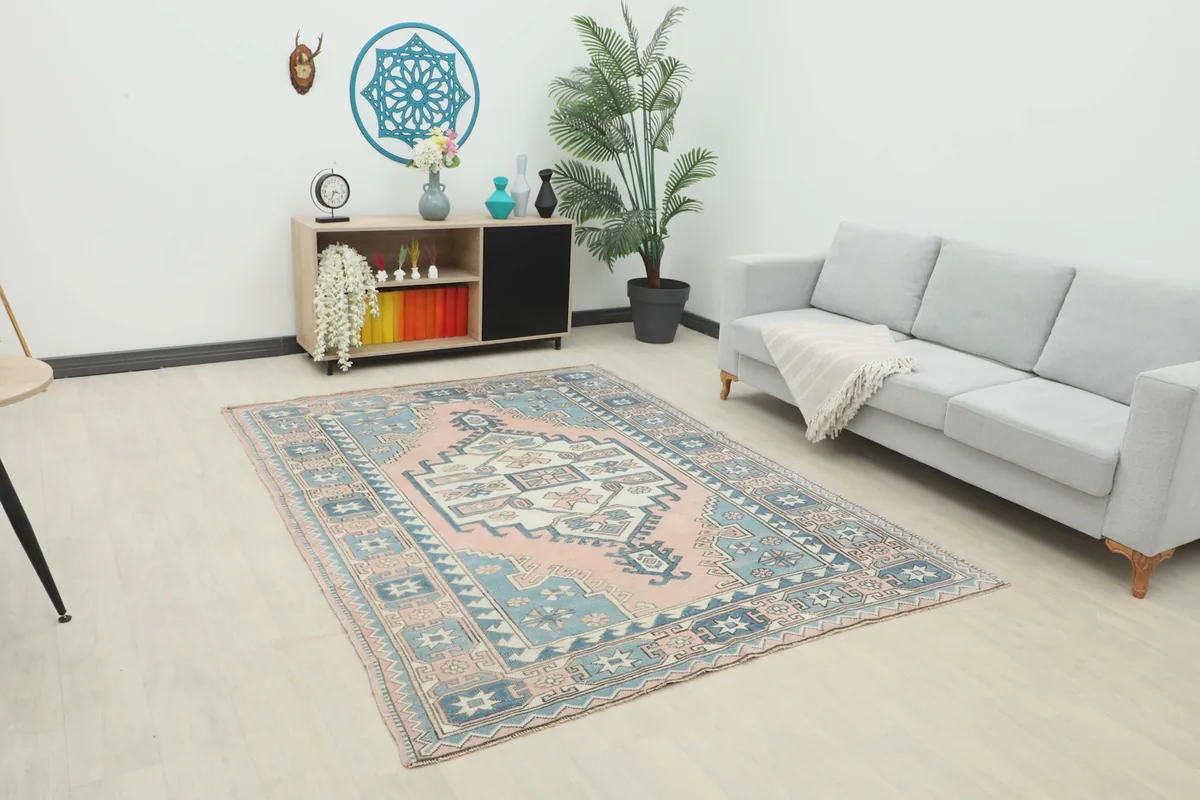 Vintage rose and blue geometric rug placed in a modern living room setting with a light gray sofa