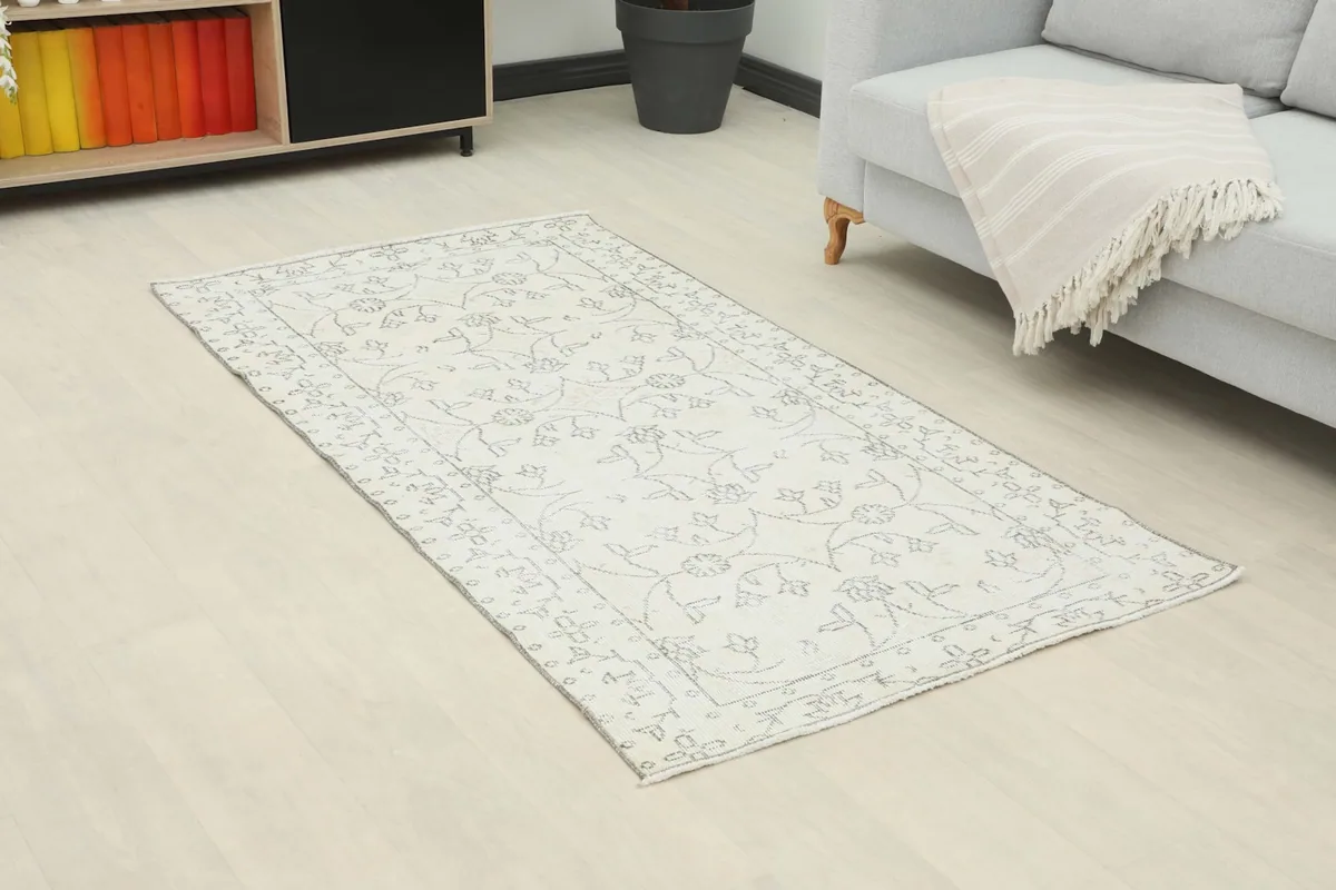 Overhead angle of the vintage rug in a living room, showing its placement on light wood flooring.