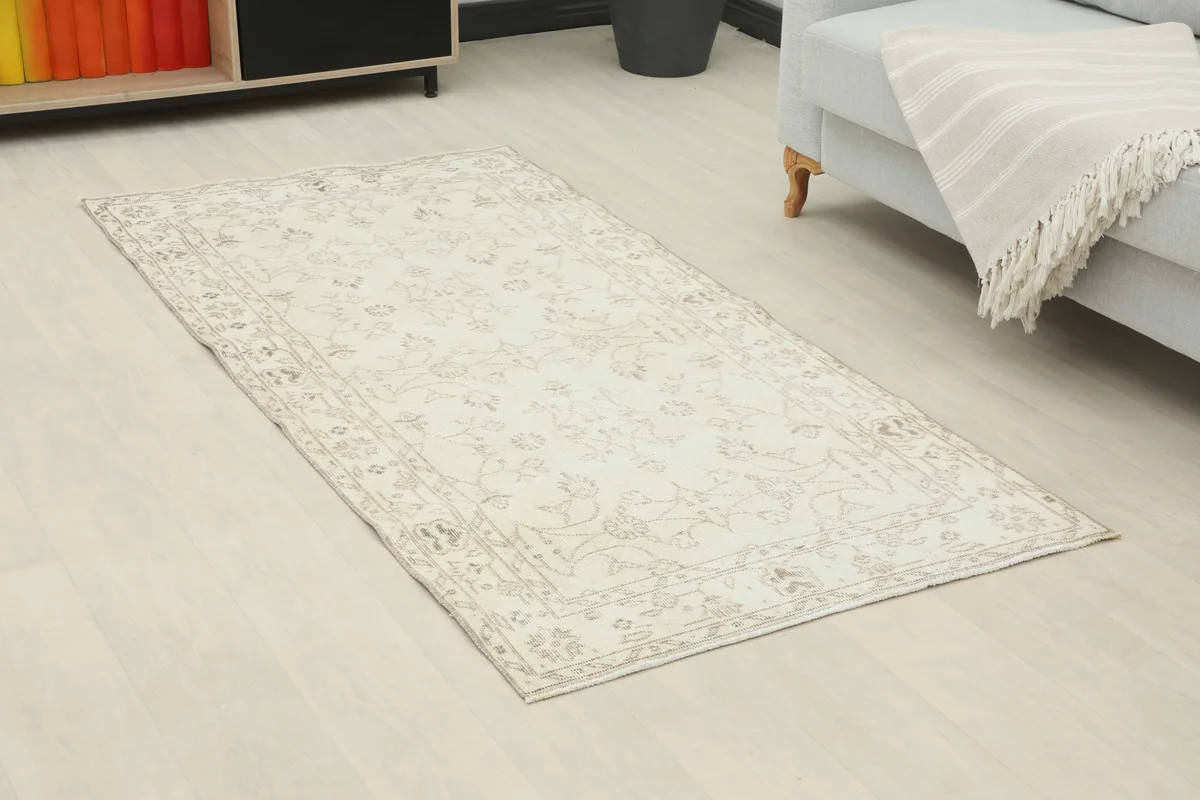 Angled view of the Beige Subtle Floral Rug on a light wood floor, highlighting its rectangular shape.