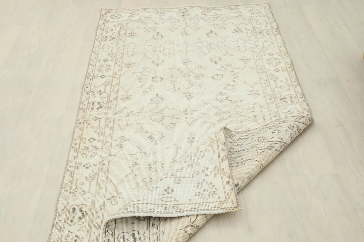 Beige Subtle Floral Rug partially folded to show flexibility and construction.