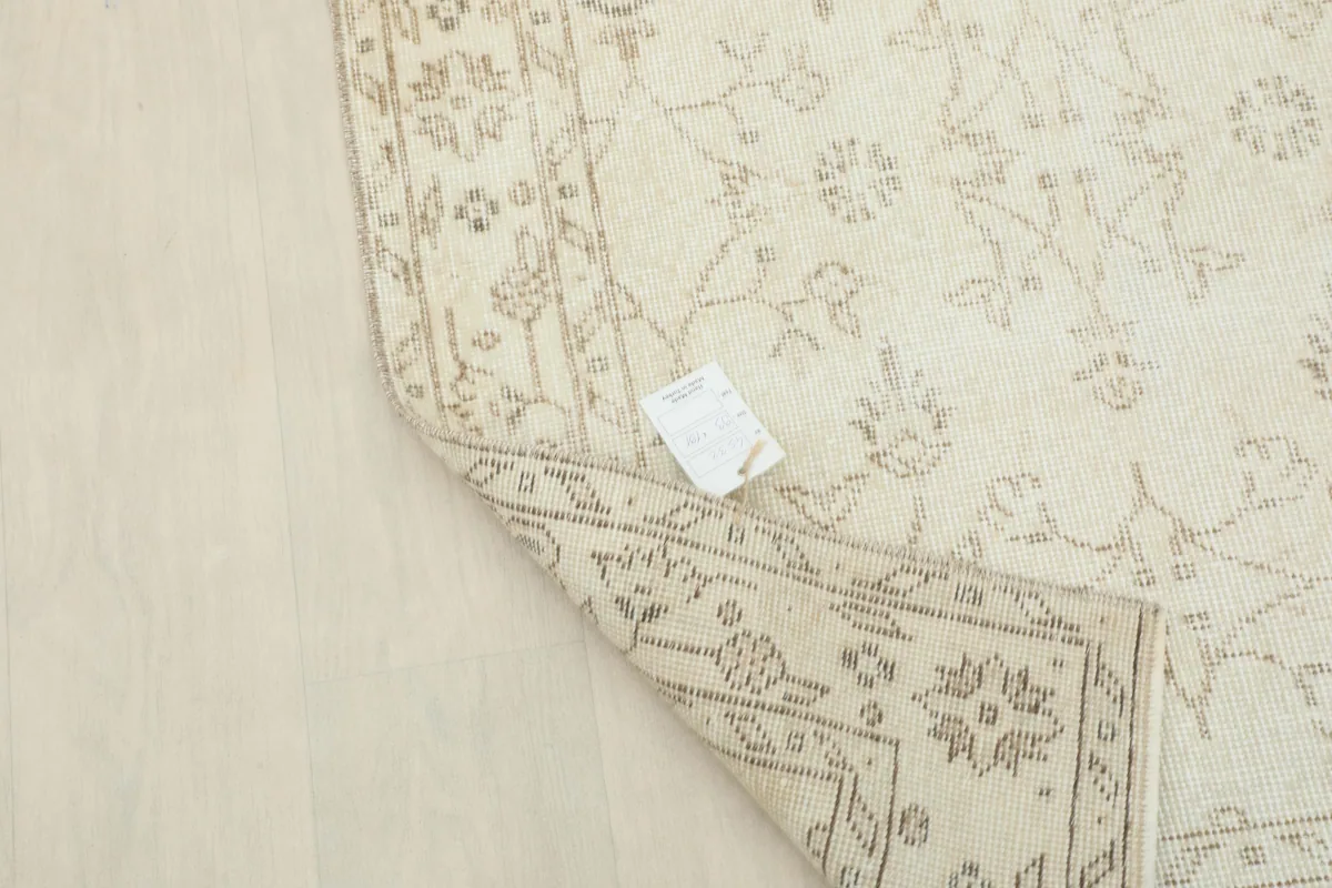 Close-up of the rug's label on the back, with the Beige Subtle Floral Rug partially folded.