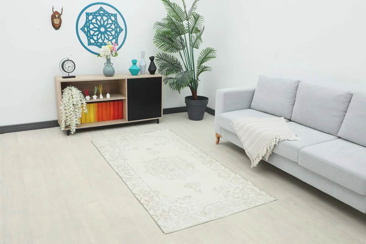 The ivory vintage rug placed in a modern living room setting next to a gray sofa.