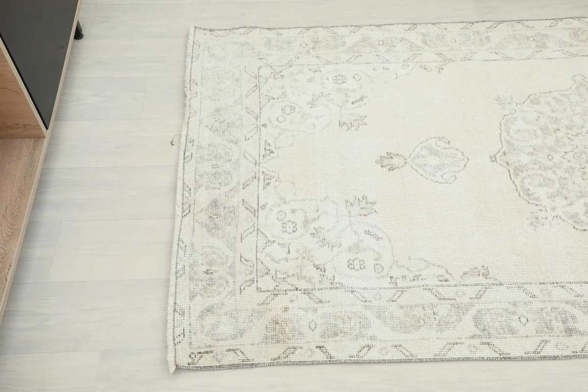 Detail of the rug's edge and border, highlighting the subtle color variations and wear.