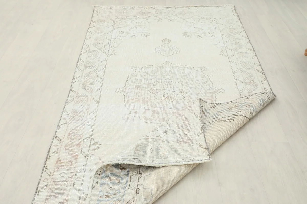 The rug partially rolled, showing the flexibility and the reverse side with visible knots.