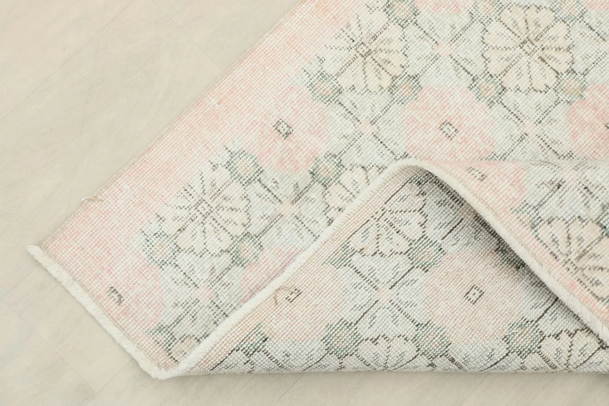 Corner of the rug folded back, revealing the cotton foundation and the reverse side of the pattern