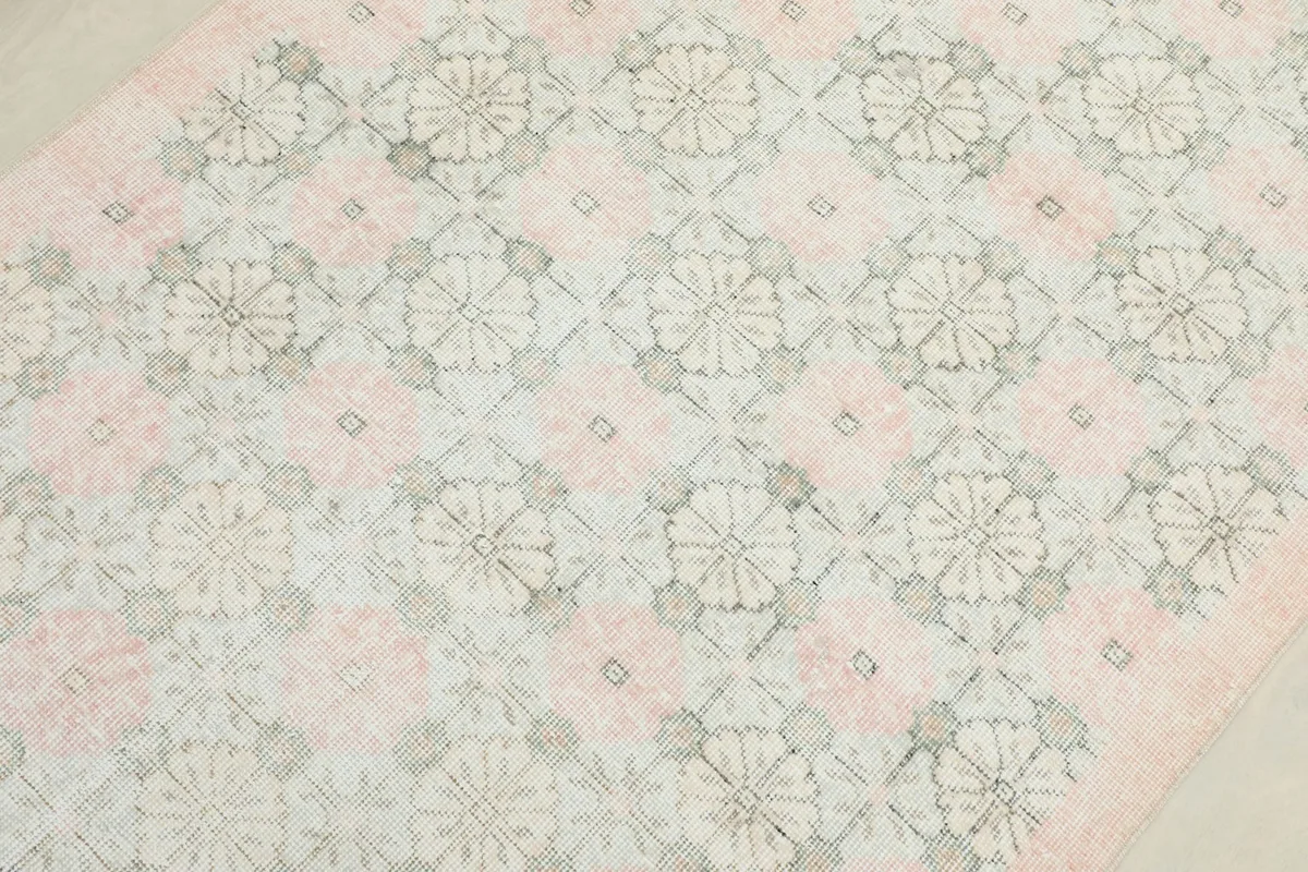 Overhead close-up of the rug's surface, revealing the geometric floral design and faded appearance